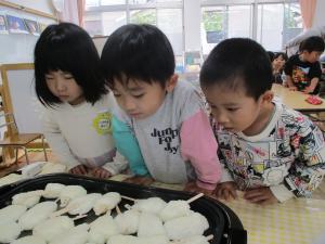 お餅が焼ける様子を見ている子どもたち　三歳児