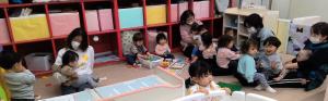 保育士と一緒にバスごっこをしている1歳児
